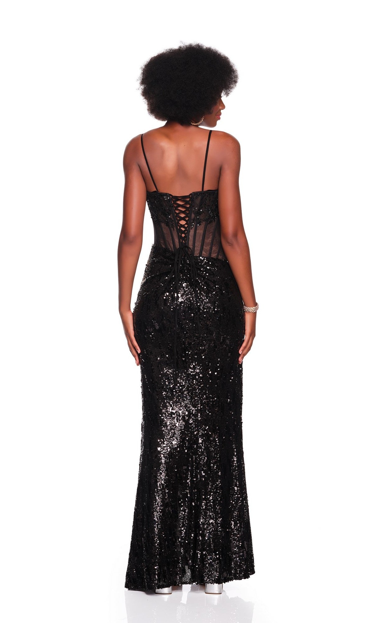 A woman stands with her back to the camera in the Dave and Johnny 12855 Long Prom Dress, a fitted black sequin gown with a corset bodice, lace-up back, and thin straps, set against a white background.